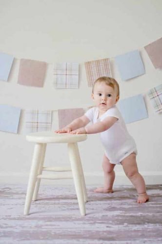 baby holding a wooden stool