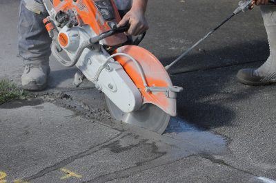 man operating a circular saw to cut through concrete