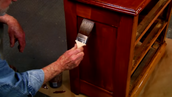 man painting wooden cabinet