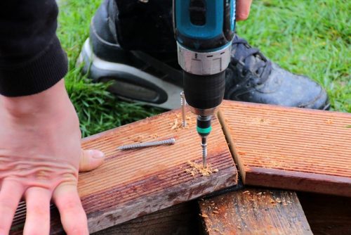 operating a hand drill on wooden frame
