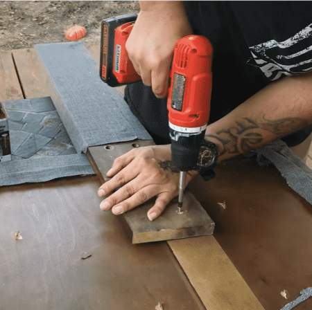 operating a red brushed drill on a wooden board