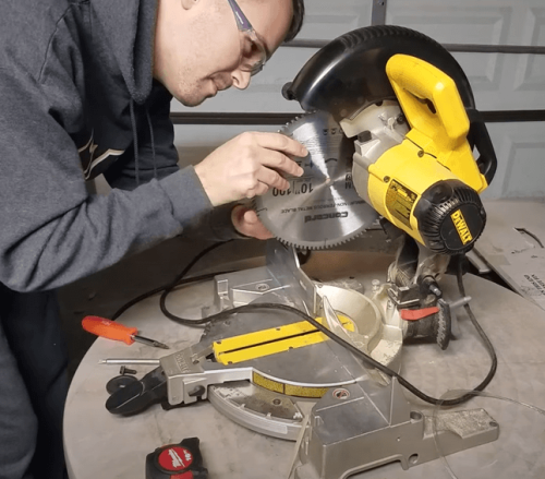 person mounting a razor blade in a miter saw
