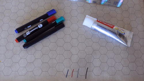 toothpaste and permanent markers on wooden surface
